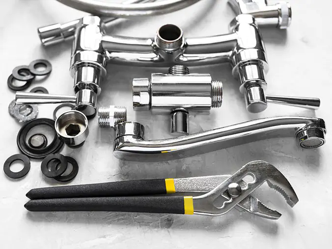 Disassembled chrome kitchen sink faucet and plumbing wrench