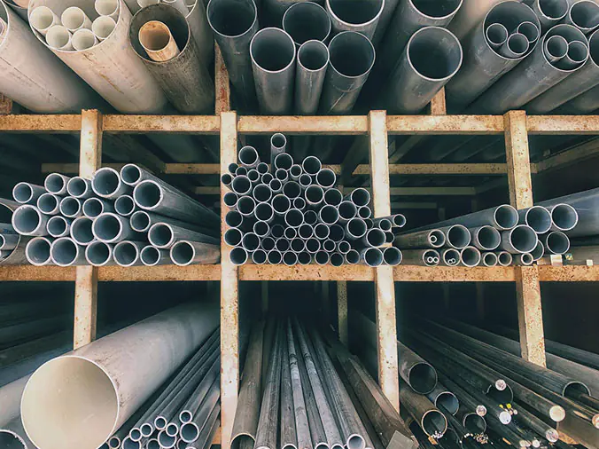 PVC anbd steel pipes on a rack in a plumbing supply warehouse